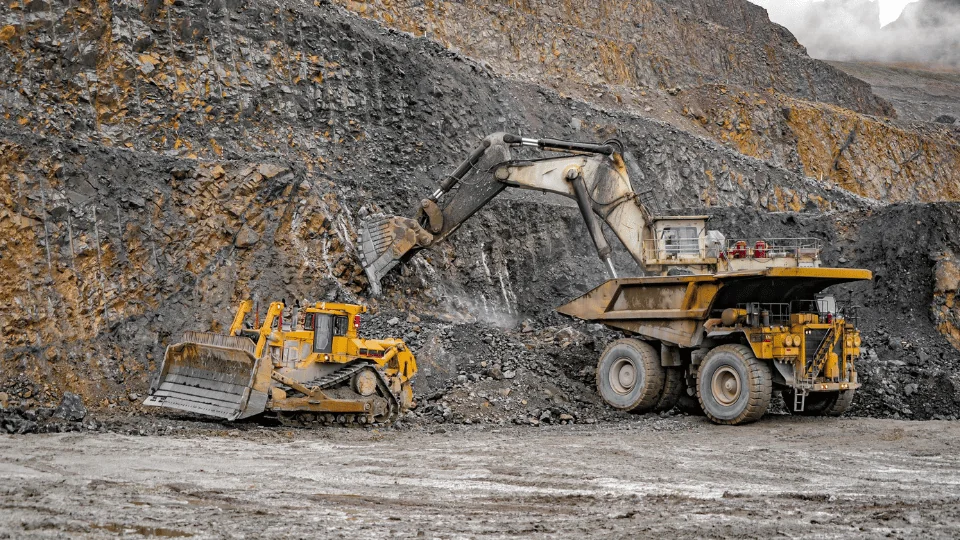 Shipping Mining Equipment excavator and dozer working on side of cliff digging rocks